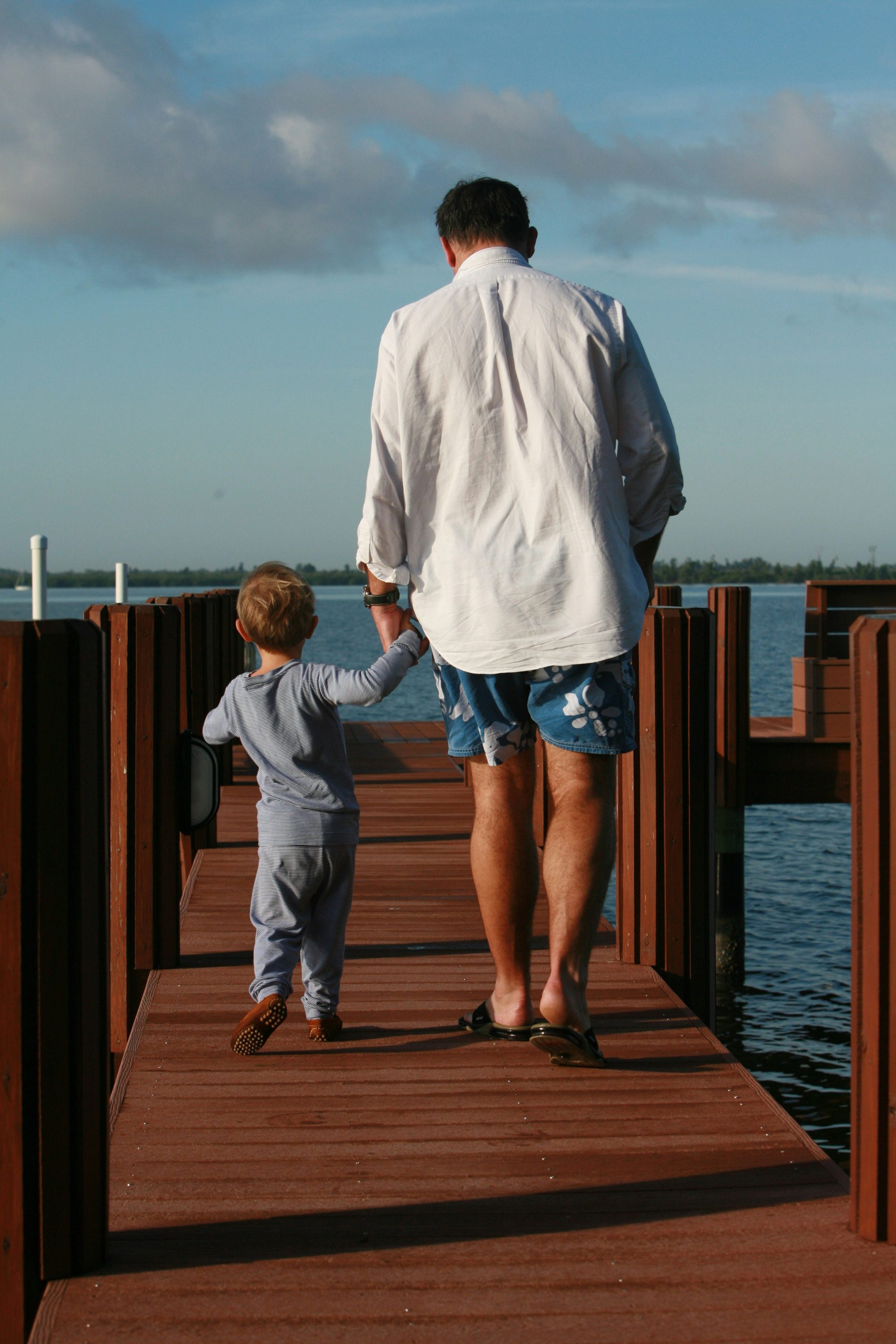 man in white dress shirt and blue denim shorts standing on dock during daytime